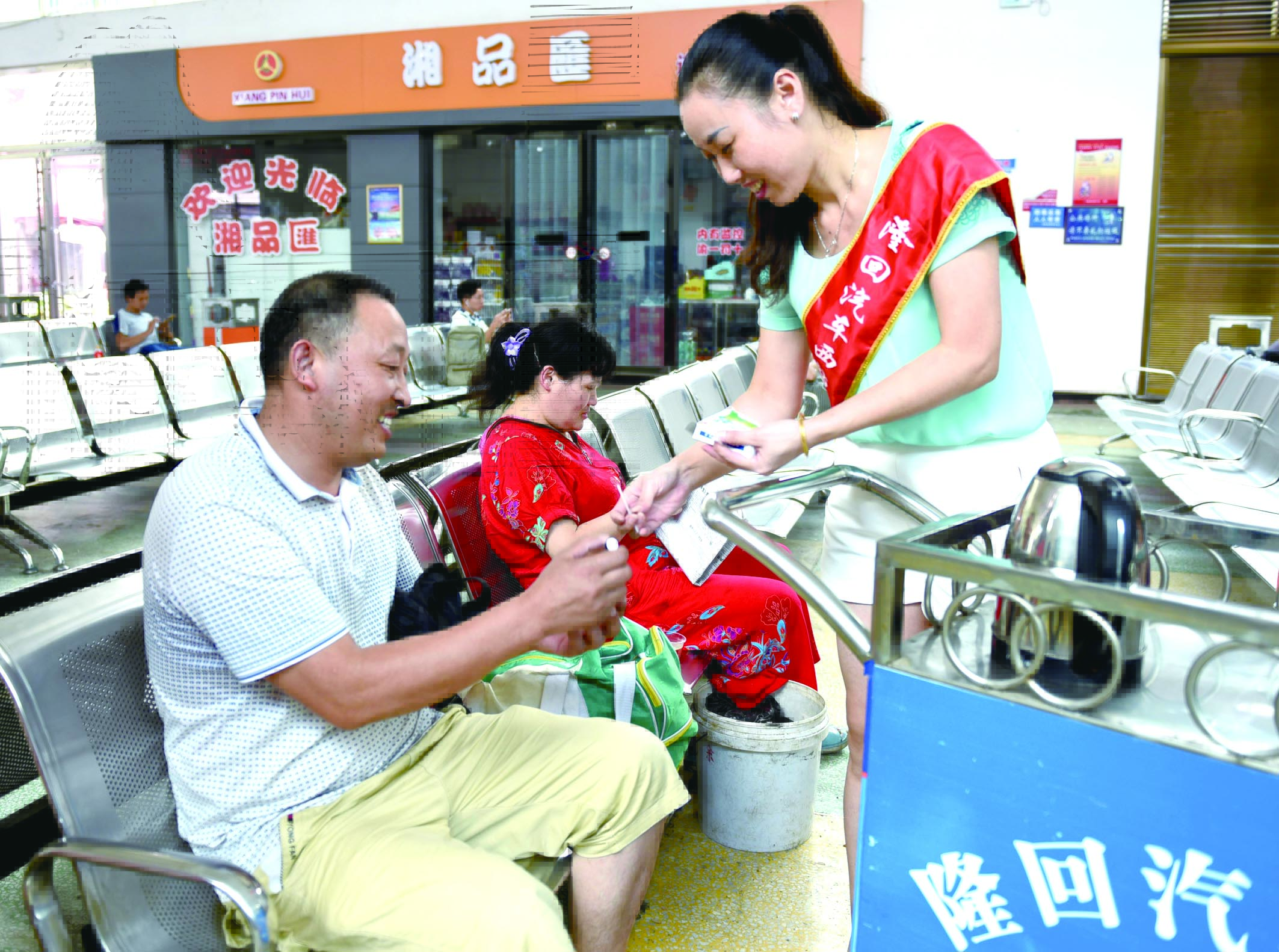 隆回分公司汽車(chē)西站工作人員正在為旅客免費(fèi)贈(zèng)送藿香正氣水。